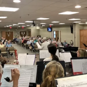 A group of people sitting in chairs with music sheets