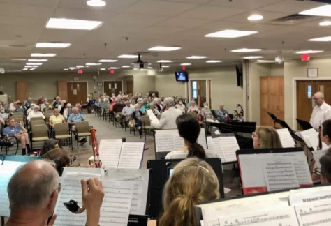 A group of people sitting in chairs with music sheets