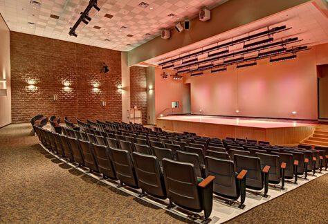 A large auditorium with a stage and chairs